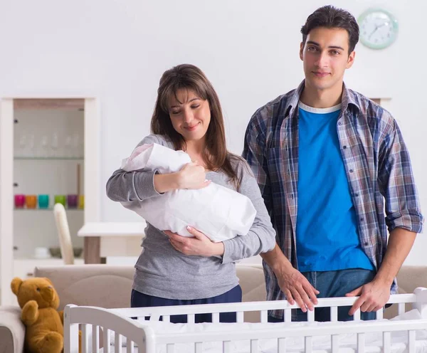 Padres jóvenes con su bebé recién nacido cerca de la cuna — Foto de Stock