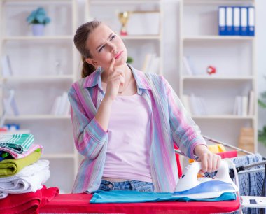 Üzücü kadın evde kıyafetleri ütülüyor.