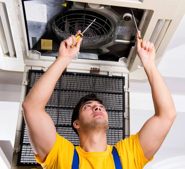 Repairman repairing ceiling air conditioning unit