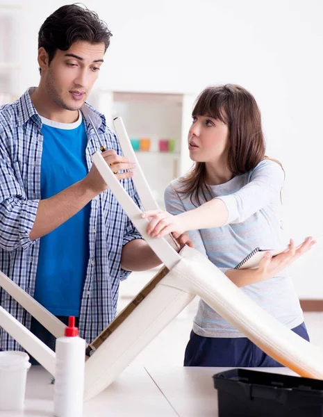 Ehefrau hilft Ehemann, kaputten Stuhl zu Hause zu reparieren — Stockfoto