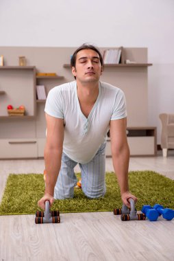 Genç adam evde spor yapıyor.