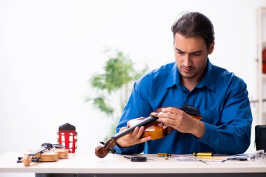 Kemanı tamir eden genç bir erkek tamirci