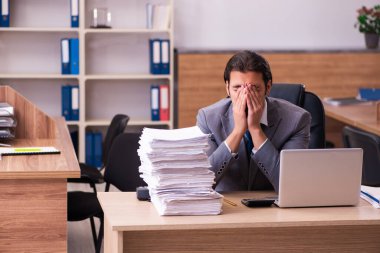 Ofisteki aşırı işten memnun olmayan genç bir erkek işçi.