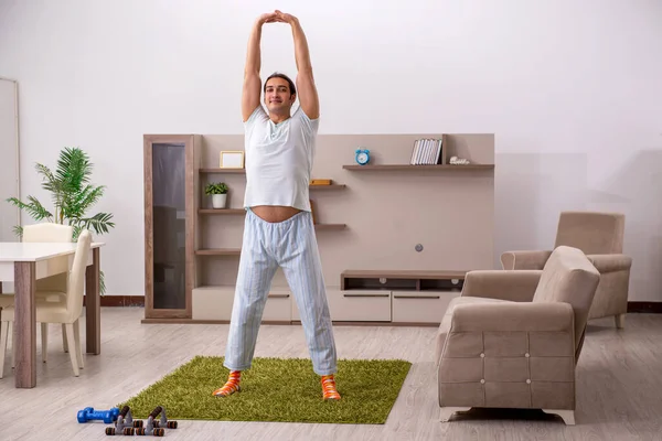 Jovem fazendo exercícios esportivos em casa — Fotografia de Stock