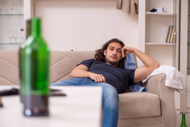 Evde alkol alan genç işsiz bir adam.