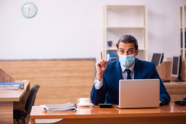 Ofiste maske takan genç bir erkek çalışan.