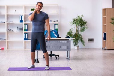 Genç yakışıklı çalışan ofiste spor egzersizleri yapıyor.