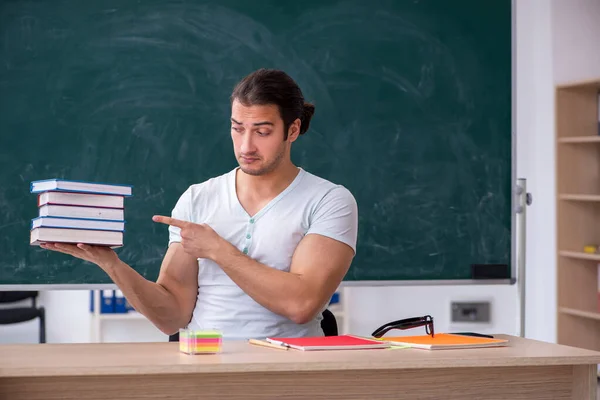 Ung mannlig lærerstudent sitter i klasserommet – stockfoto