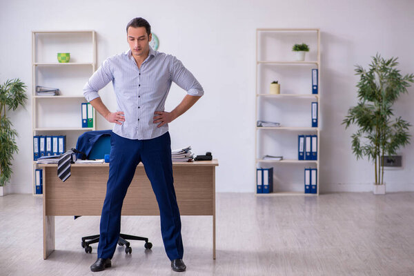 Молодой красивый работник делает упражнения в офисе