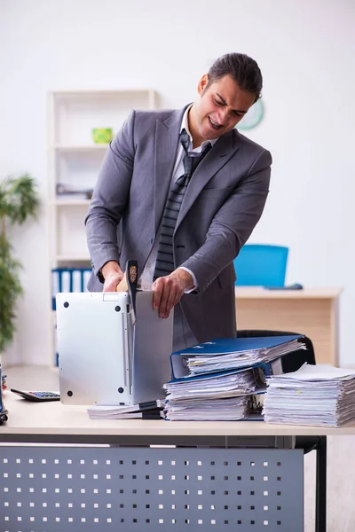 Jeune employé en colère contre le travail excessif tenant hachette — Photo