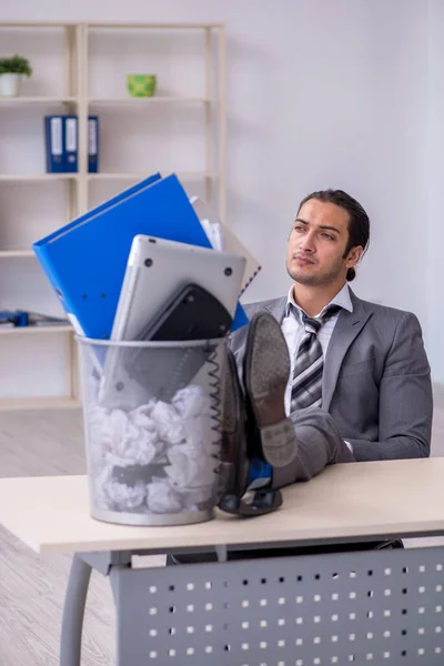 Уволенный молодой бизнесмен с мусорным баком в офисе — стоковое фото