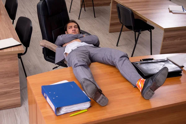 Jonge mannelijke werknemer die op de werkplek slaapt — Stockfoto