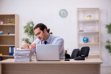 Genç erkek çalışan ofiste oturuyor.