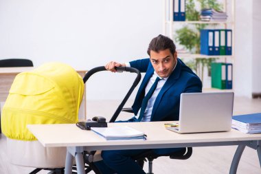 Genç erkek çalışan işyerinde çocuğa bakıyor.