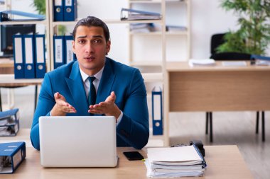 Genç yakışıklı çalışan ofiste oturuyor.