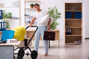 İş yerinde yeni doğan bebeğe bakan genç bir erkek işçi.