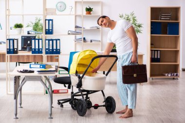 İş yerinde yeni doğan bebeğe bakan genç bir erkek işçi.