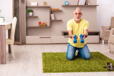 Yaşlı adam evde spor egzersizleri yapıyor.