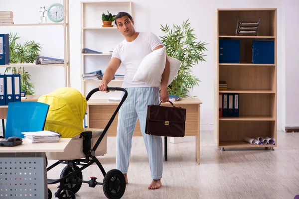 İş yerinde yeni doğan bebeğe bakan genç bir erkek işçi.