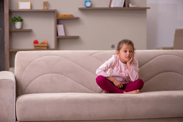 Маленькая девочка сидит одна дома — стоковое фото