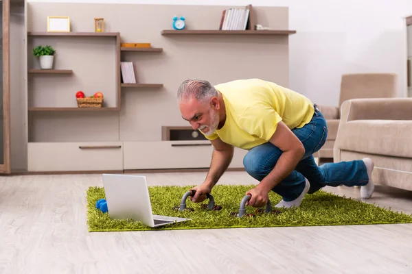 Yaşlı adam evde spor egzersizleri yapıyor.