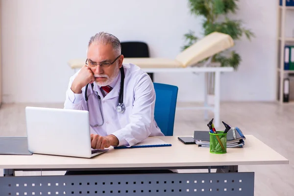 Oude mannelijke arts werkzaam in de kliniek — Stockfoto