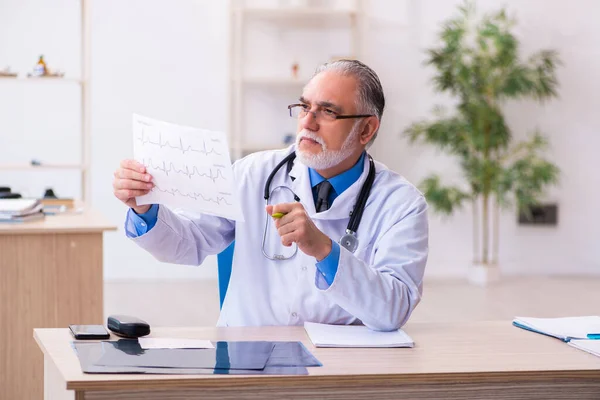 Oude mannelijke arts cardioloog op zoek elektrocardiogram — Stockfoto