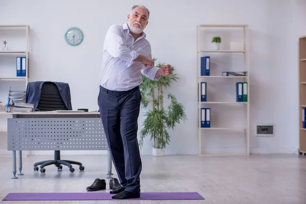 Empleado varón envejecido haciendo ejercicios físicos durante el descanso — Foto de Stock