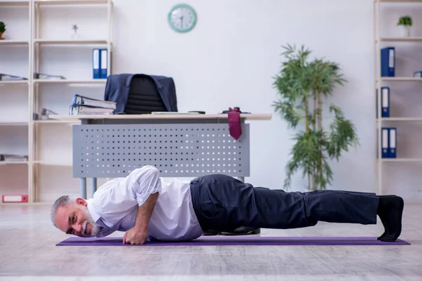 Ältere männliche Mitarbeiter machen in der Pause körperliche Übungen — Stockfoto