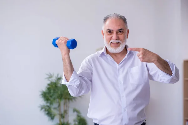 Åldrad manlig anställd som motionerar under pausen — Stockfoto