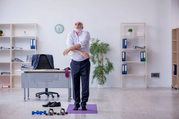 У віці чоловік працівник робить фізичні вправи під час перерви — стокове фото