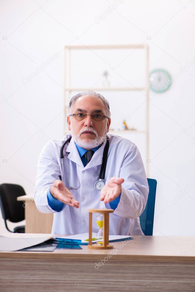 Old male doctor radiologist in time management concept