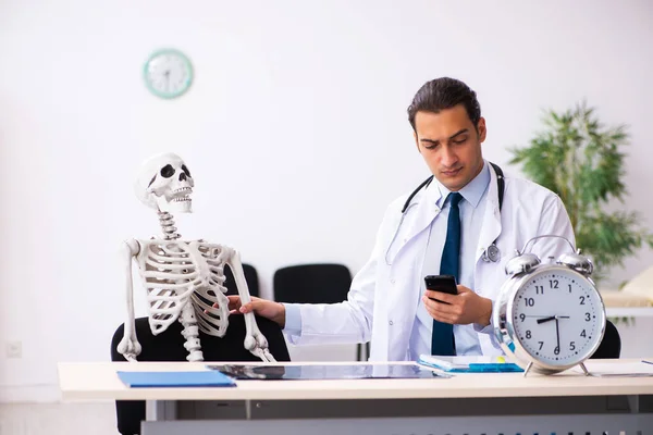 Jonge mannelijke arts en skelet patiënt in time management concep — Stockfoto