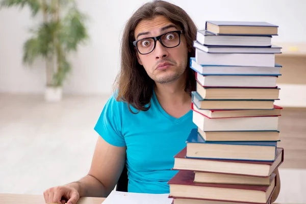 Fiatal férfi diák és sok könyv az osztályban — Stock Fotó
