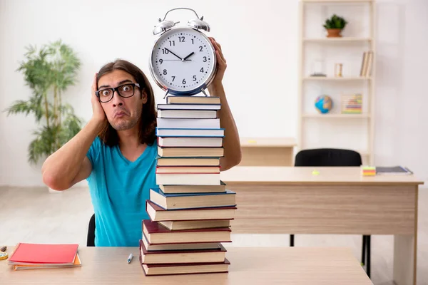 Young male student and a lot of books in the class — Stock Photo, Image