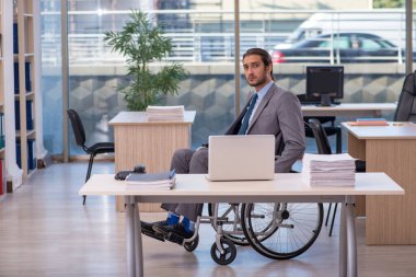Ofiste çalışan, tekerlekli sandalyede çalışan genç bir erkek.