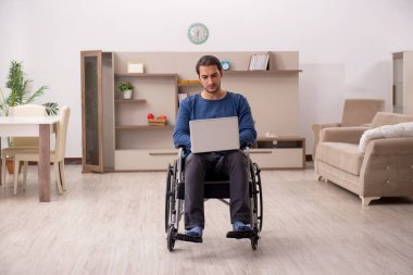 Evde acı çeken tekerlekli sandalyedeki genç adam.