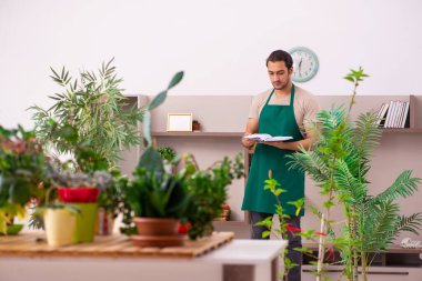 Evin içinde bitkileri olan genç bir erkek bahçıvan.