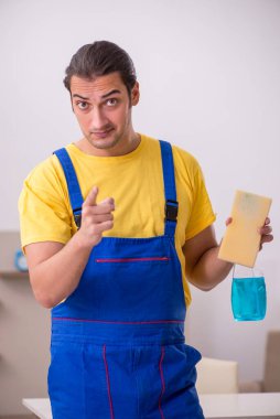 Genç erkek müteahhit evi temizliyor.