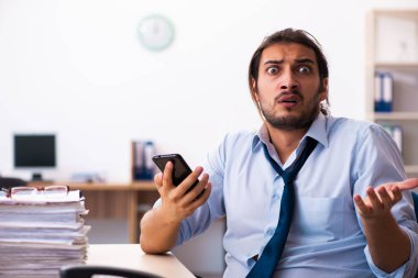 Ofisteki aşırı işten memnun olmayan genç bir erkek işçi.