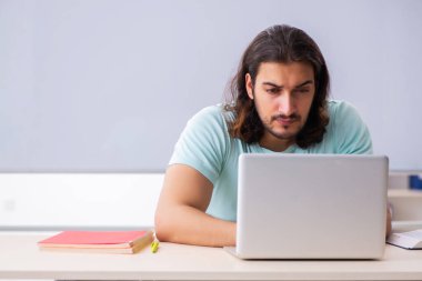 Genç erkek öğrenci tele-eğitim konsepti sınavlarına hazırlanıyor.