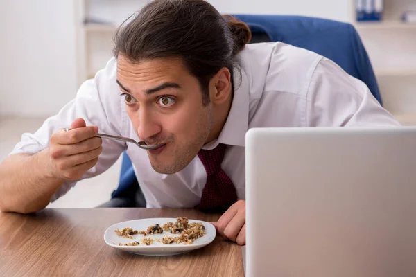 Funcionário masculino faminto comendo trigo sarraceno durante o intervalo — Fotografia de Stock