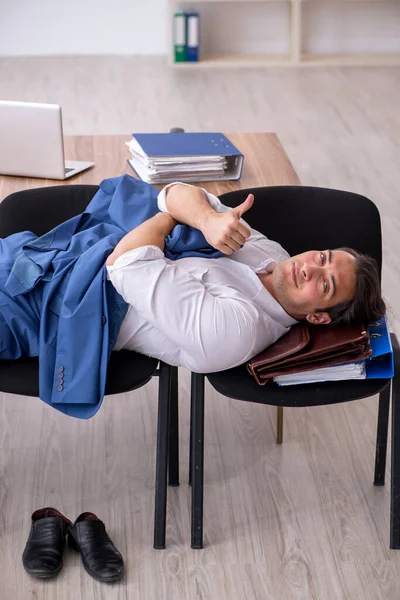 Νεαρός υπάλληλος που κοιμάται στο γραφείο σε καρέκλες — Φωτογραφία Αρχείου