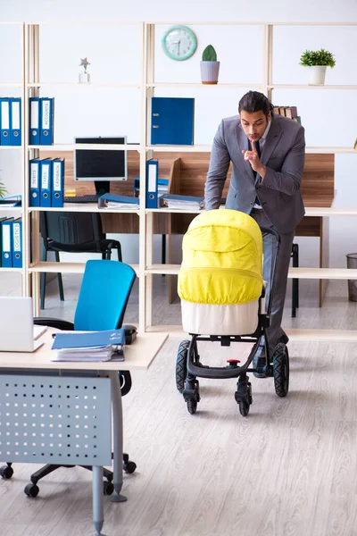 Joven empleado masculino que cuida del recién nacido en el lugar de trabajo — Foto de Stock