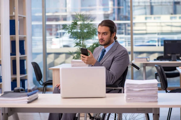 Young male employee in wheel-chair working in the office — Stock Photo, Image