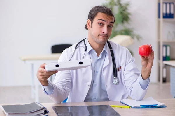 Młody lekarz dietetyk trzymający jabłko i pudełko po pizzy — Zdjęcie stockowe