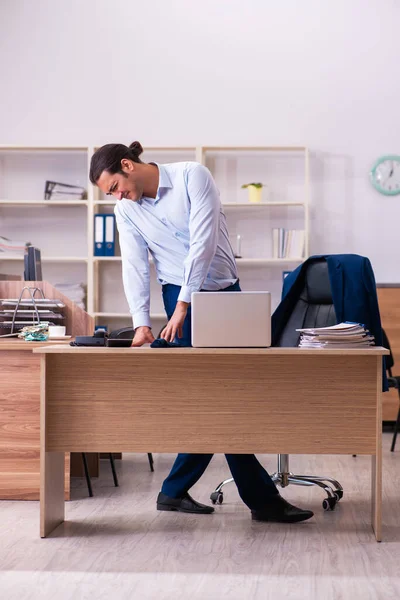 Junge männliche Angestellte leidet an Rückenschmerzen am Arbeitsplatz — Stockfoto