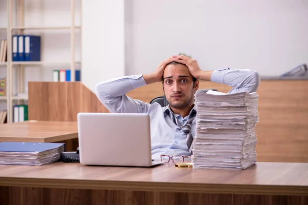 Jonge mannelijke werknemer ongelukkig met overmatig werk in het kantoor — Stockfoto