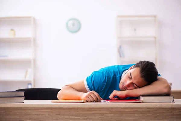 Erschöpfte männliche Schüler bereiten sich im Klassenzimmer auf die Prüfungen vor — Stockfoto