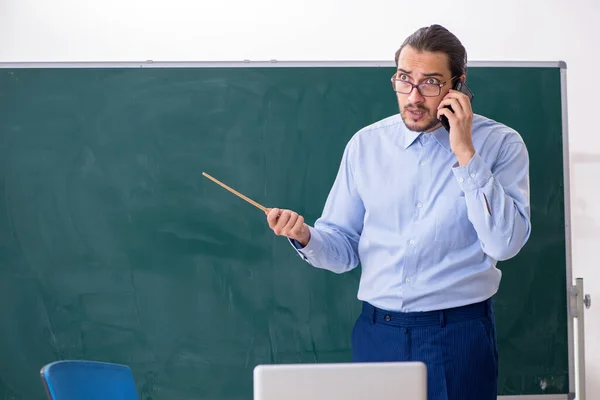 Ung manlig lärare i klassrummet framför green board — Stockfoto